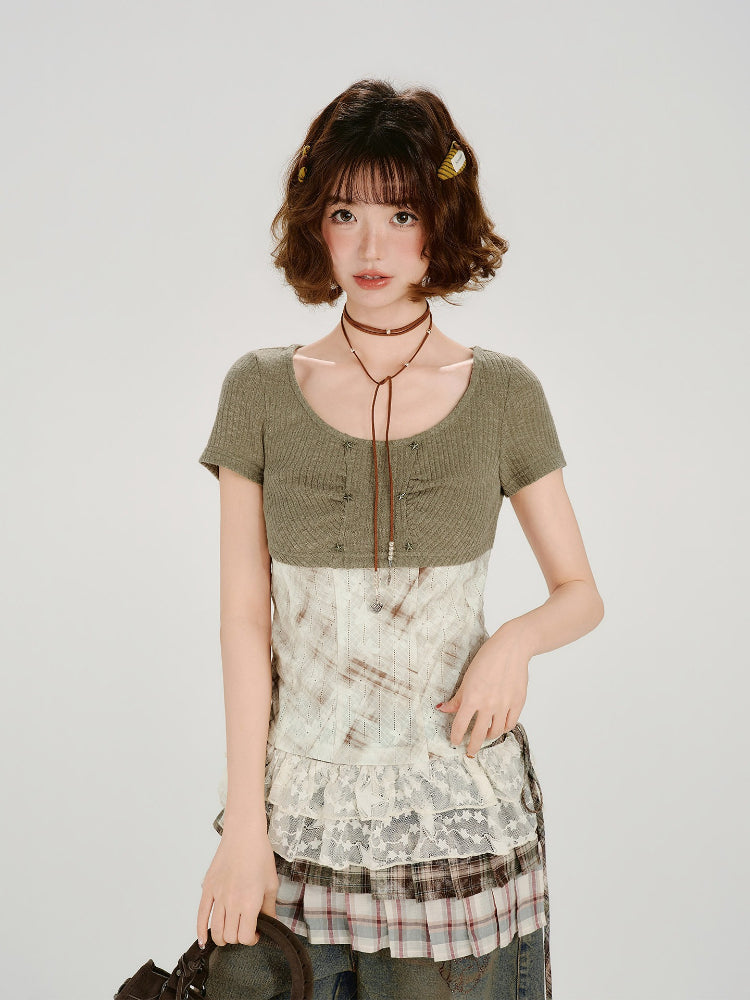Woman wearing a green ribbed knit short sleeve top with a white and brown patterned corset-style overlay and lace trim.