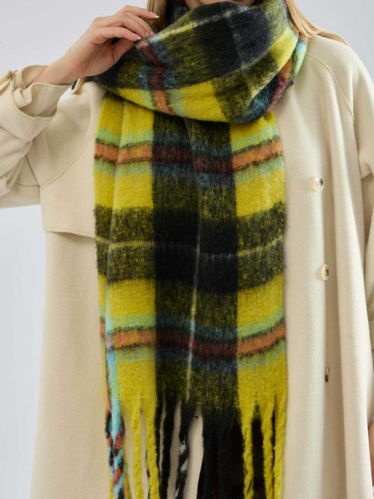 woman wearing a grey coat and light pants with a pink and tan plaid scarf around her neck