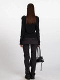 Back view of a woman wearing a black long-sleeve asymmetrical knit sweater