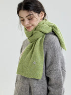 Side profile of a woman wearing a light green ribbed knit scarf.