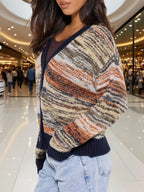Side view of a woman wearing a multicolored striped knit cardigan with a V-neck and button-up front