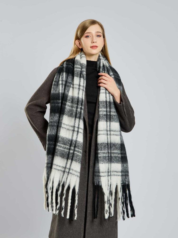 Woman wearing a black and white plaid scarf with fringe detail