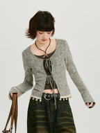 Woman holding a denim bag, wearing a grey ribbed knit tie-front cardigan