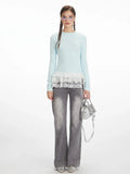 Woman wearing a light blue long-sleeve top with white lace trim and grey wide-leg jeans