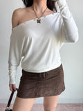 Model adjusting the sleeve of the white off-the-shoulder top.