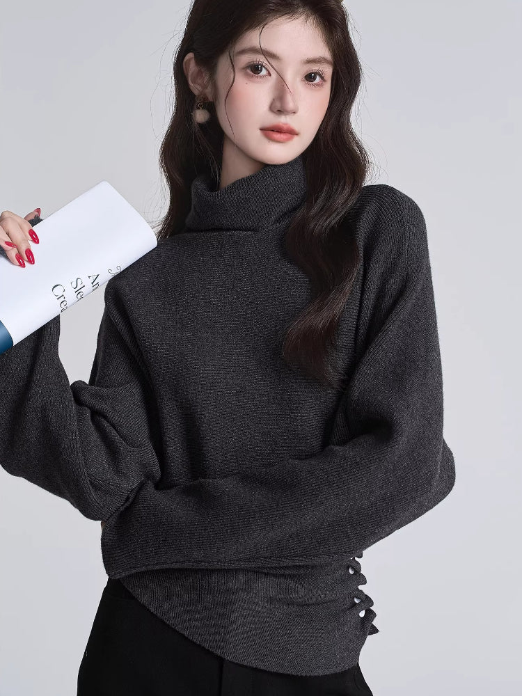 Woman wearing a dark grey high neck knit sweater with side buttons