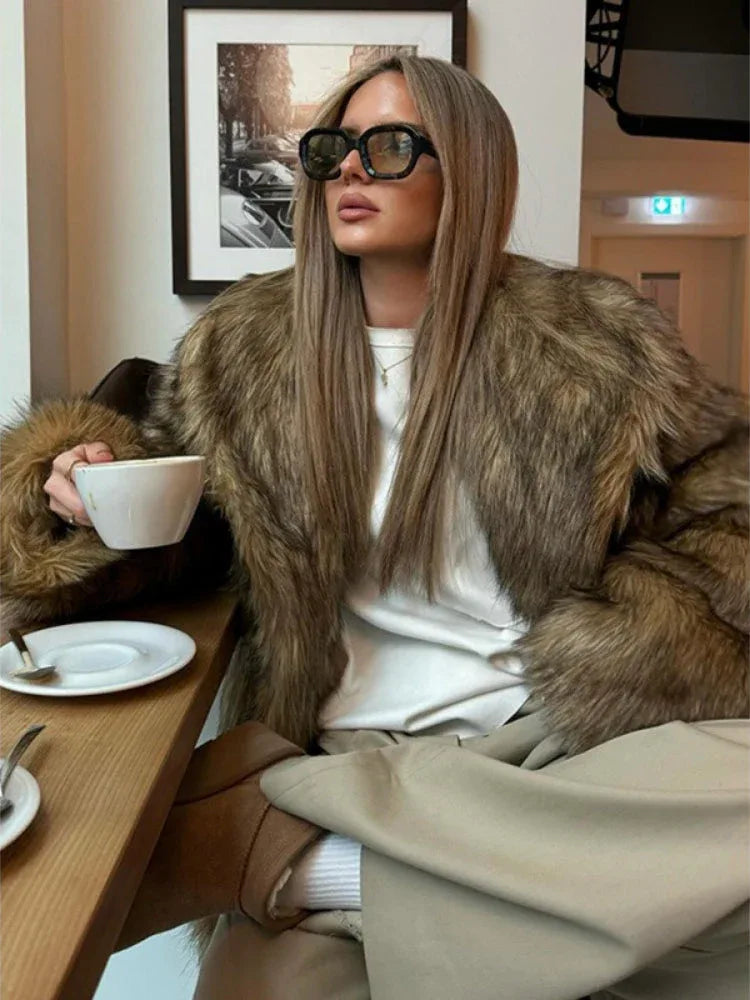 Close-up of a woman in a faux fur jacket and sunglasses, drinking coffee.
