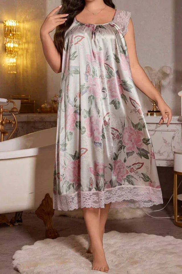 Woman wearing a light grey satin midi nightgown with a pink floral and butterfly print, featuring lace cap sleeves and hem. Main image