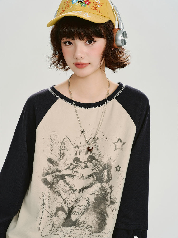 Model posing with a shoulder bag, wearing a cream and navy long-sleeve graphic tee.