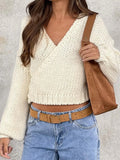 Woman wearing a cream chunky knit wrap sweater with long sleeves and a V-neck.