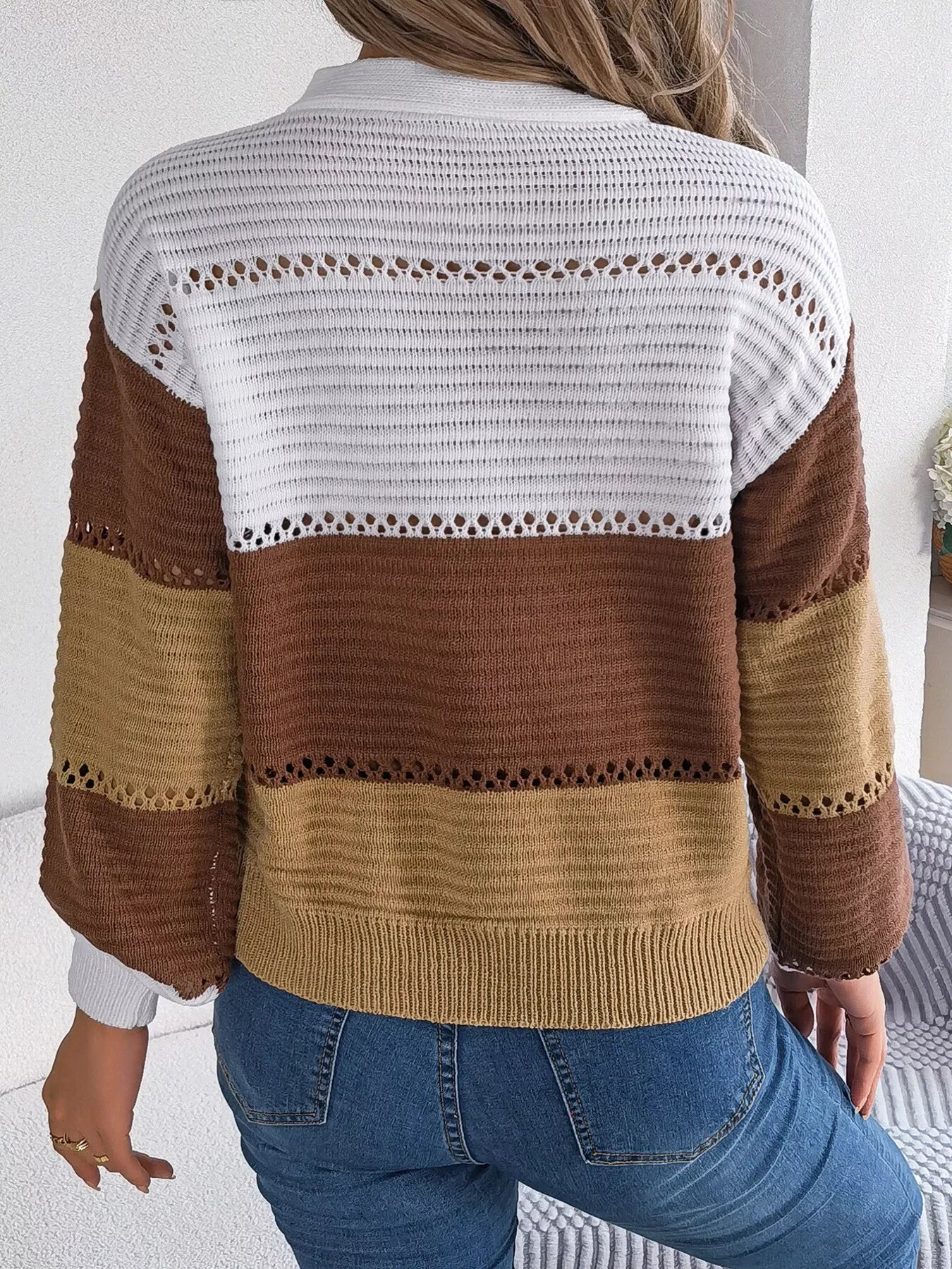 Back view of a woman in a color block knit sweater with open knit details.