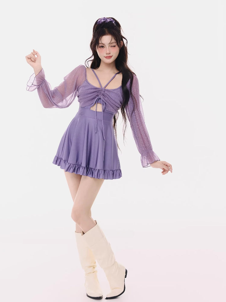 Full-body shot of the woman in the purple swim dress and cream boots, posing