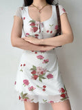 Woman wearing a white short-sleeved mesh dress with a strawberry, cherry, and rose print.