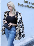 Woman holding a black clutch purse with a leopard print faux fur jacket draped over her shoulders