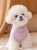 White bichon frise dog wearing a lavender fluffy dog sweater with a white 