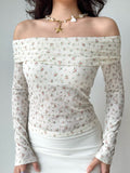 Woman wearing a white off-the-shoulder top with a floral print and long sleeves.