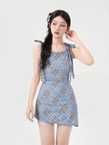 Side view of a woman in a blue plaid mini dress with tie shoulder detailing
