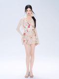 Full body shot of a woman in a floral print tiered dress and sheer cardigan.