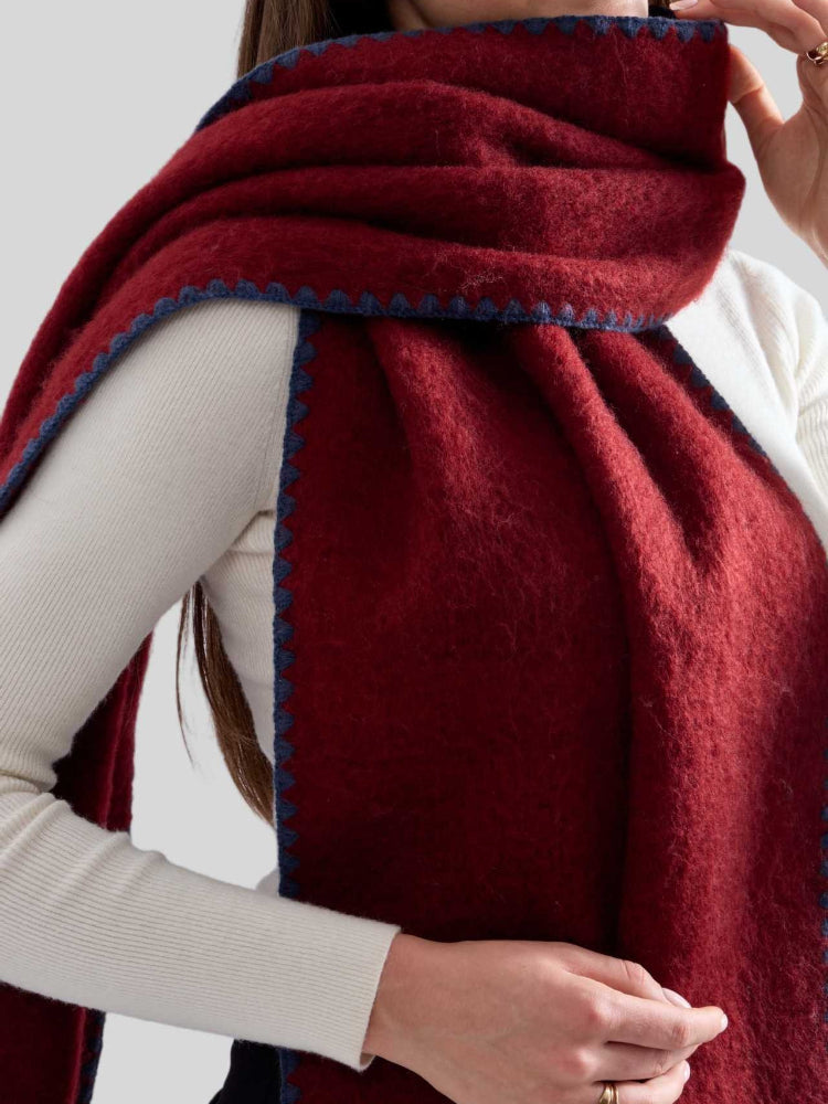 Detail view of the textured fabric and stitching on a burgundy scarf.
