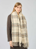 Full body shot of a woman in a brown coat with a cream and brown plaid scarf.