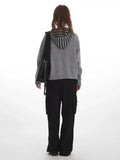 Back view of woman in gray knit sweater with striped hood and black cargo pants
