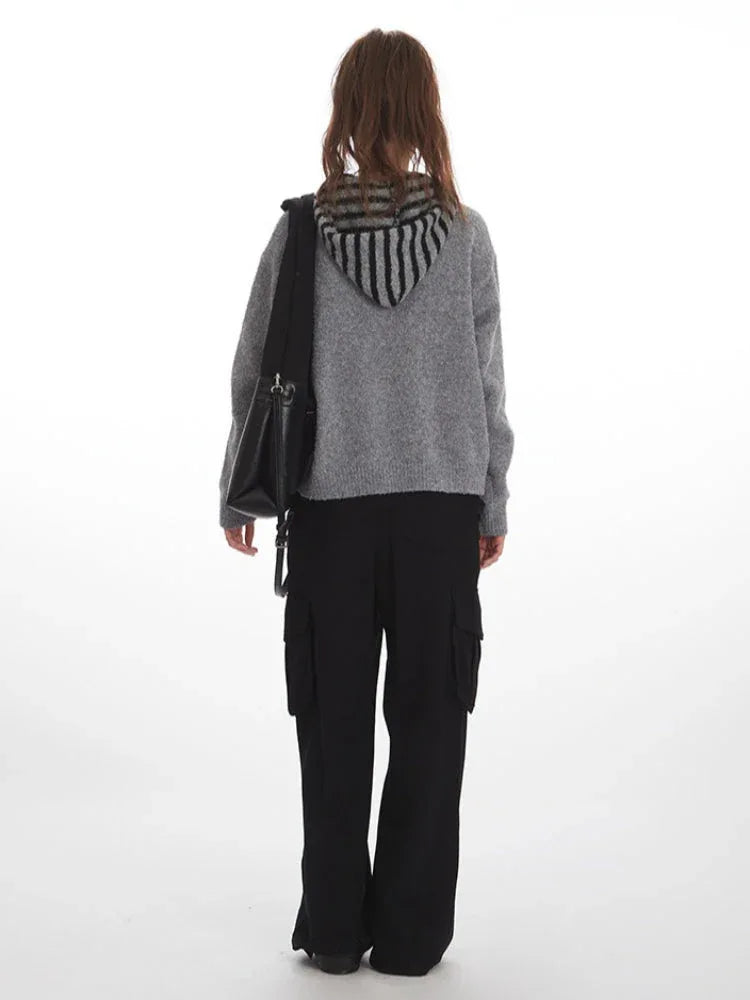 Back view of woman in gray knit sweater with striped hood and black cargo pants