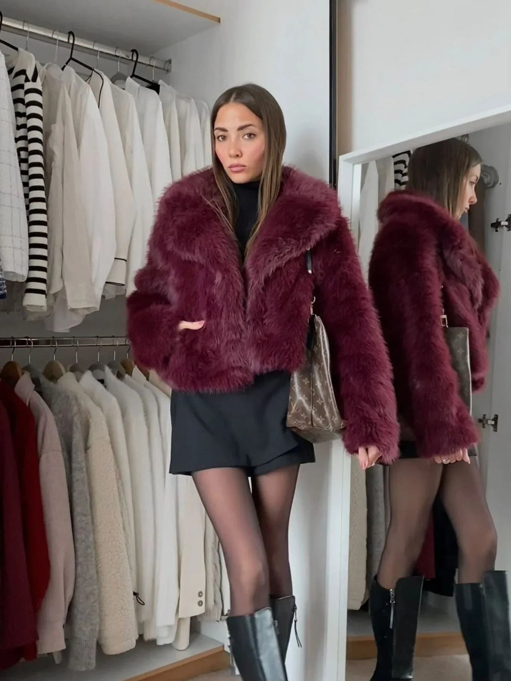 Woman wearing a burgundy faux fur jacket and black shorts indoors.
