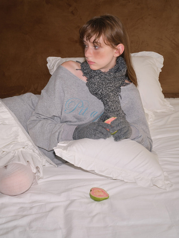Close-up of a young woman wearing a grey sweatshirt with a graphic print and a grey scarf.