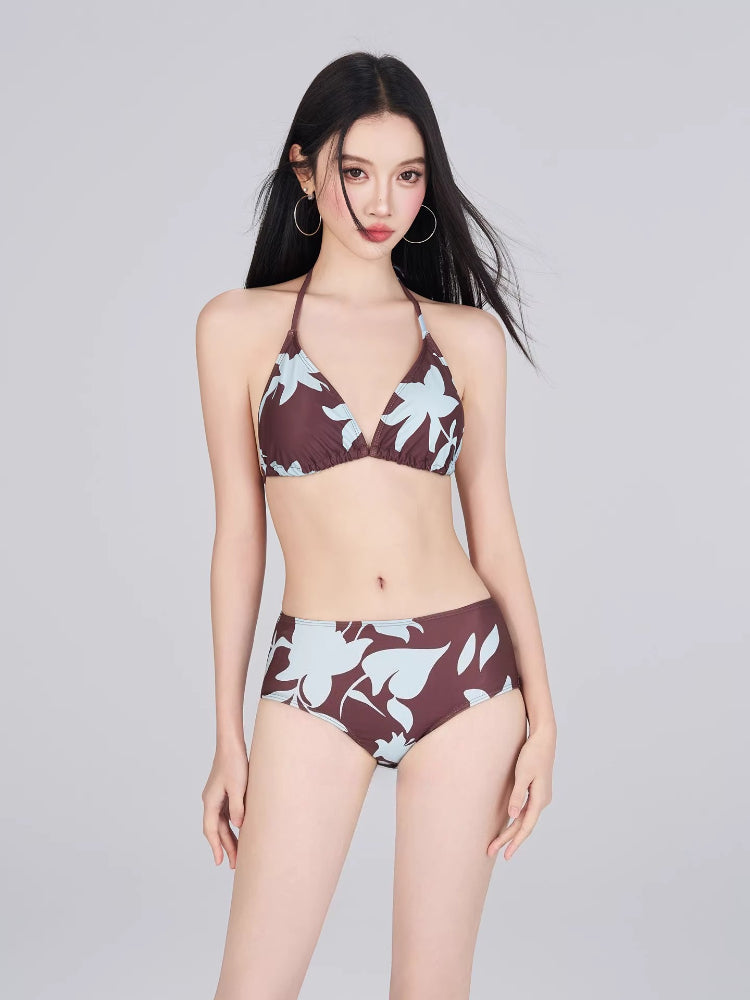Woman wearing a brown and light blue floral print bikini with a halter top and high-waisted bottoms.