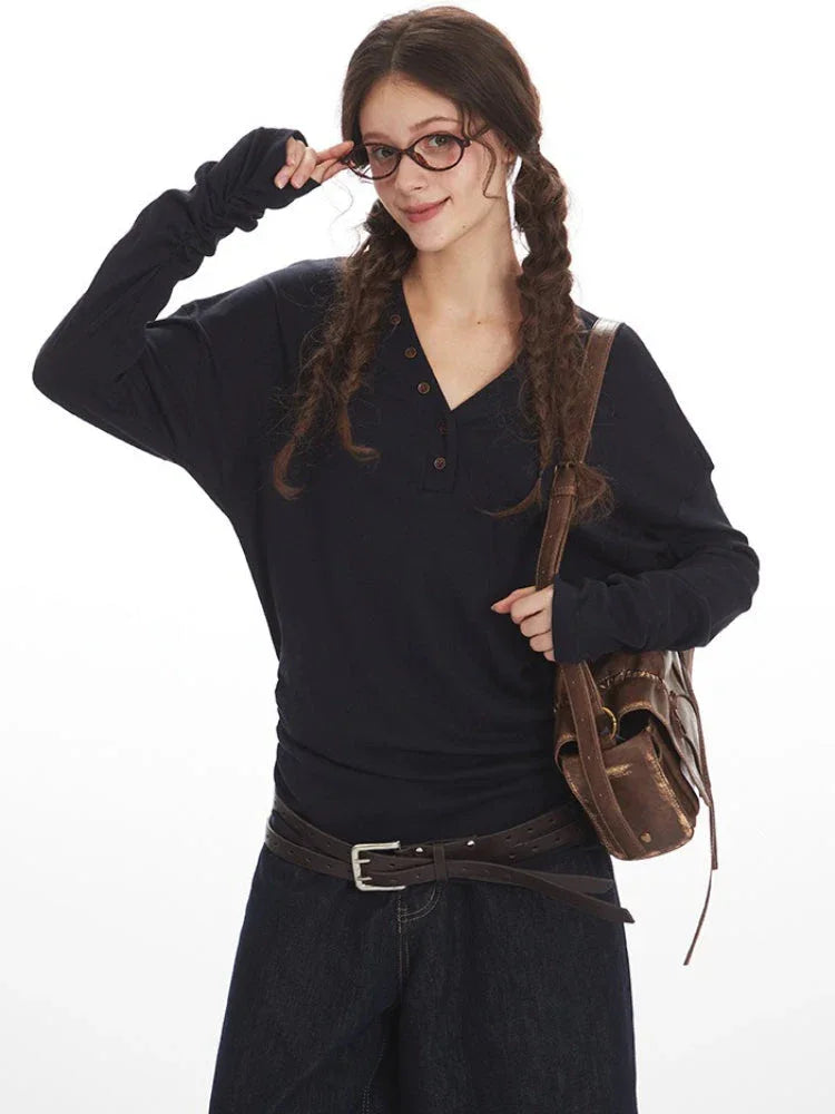 Close-up of a woman in a navy long-sleeve henley shirt and dark wash culottes.