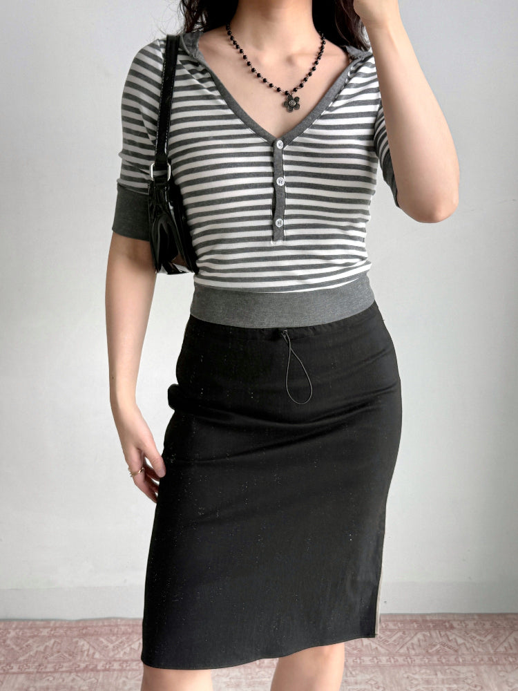 Side view of a woman wearing a striped cropped knit top and black skirt