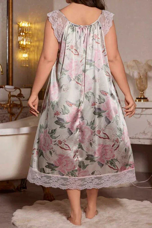 Back view of a woman in a light grey satin nightgown with a pink floral and butterfly print, lace cap sleeves, and lace hem.