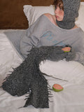 Young woman in grey loungewear set including a sweatshirt, scarf, and gloves, holding fruit.