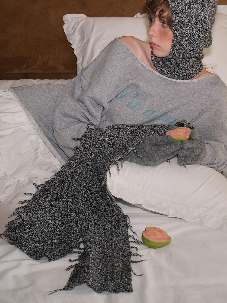 Young woman in grey loungewear set including a sweatshirt, scarf, and gloves, holding fruit.