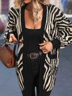 Woman holding a phone and a purse while wearing a zebra print cardigan.