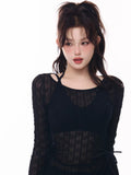 Close-up of a woman wearing a black sheer long-sleeve top with a halter bikini top underneath.