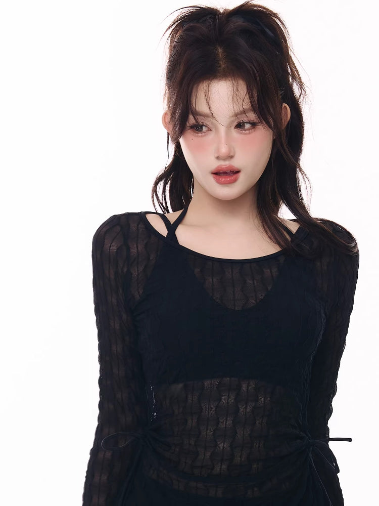 Close-up of a woman wearing a black sheer long-sleeve top with a halter bikini top underneath.