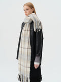 Side view of a woman wearing a plaid scarf with blue and beige squares and a fringed hem.