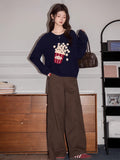Full body shot of a woman wearing a navy blue knit sweater with a popcorn graphic and brown cargo pants