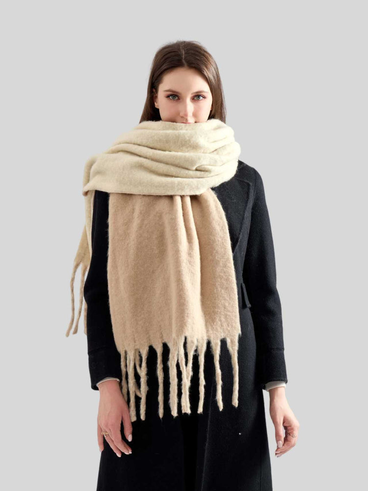 Woman wearing a beige oversized scarf with fringe detail