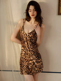 Woman looking down while wearing a leopard print satin slip dress.
