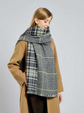 Woman in a camel coat with a black and white houndstooth and plaid scarf.