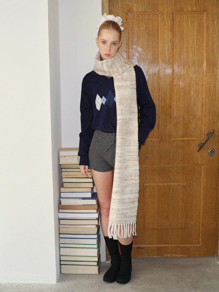 Model wearing a navy argyle V-neck sweater, grey knit shorts, and a striped scarf with fringe detail.