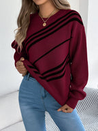 Woman in a maroon and black striped sweater, lifting the hem to show blue denim jeans.