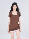 Front view of a woman in a brown swimsuit with a ruffled hem and plaid underlayer, showcasing the design details