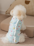 Rear view of a Bichon Frise dog wearing a light blue padded vest with a cloud and strawberry print.