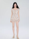 Full-body view of a woman in a cream-colored butterfly print mini dress with flutter sleeves.