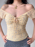 Close-up of a yellow floral print mesh top with a sweetheart neckline and ruched detail