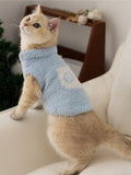 A cat in a light blue fluffy knit pet vest with a mock neck, looking upwards.