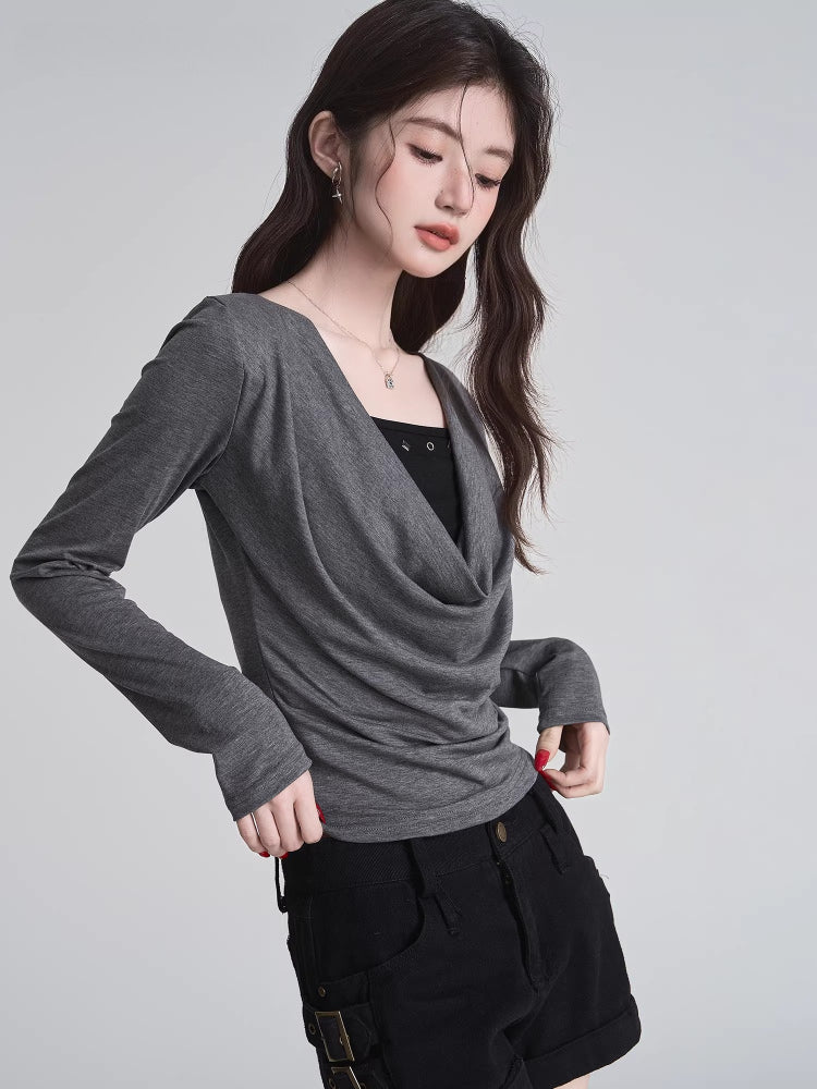 Woman adjusting grey draped cowl neck long sleeve top